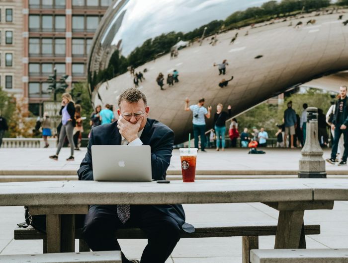 Un homme en tenue de ville travaillant sur son ordinateur assis à une table à Chicago © Tim Gouw via Pexels